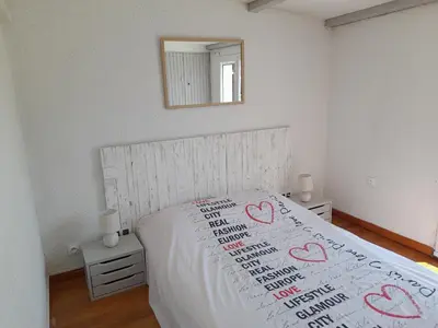 a bed with a white bedspread with hearts on it at Villa, maison bord de mer climatisée in Poggio-Mezzana