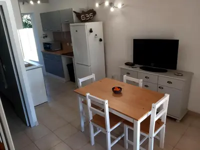 a kitchen with a table and a kitchen with a refrigerator at Villa, maison bord de mer climatisée in Poggio-Mezzana