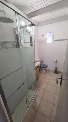 a bathroom with a glass shower and a toilet at Villa, maison bord de mer climatisée in Poggio-Mezzana
