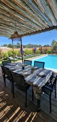 a wooden table with chairs and an umbrella next to a pool at Casa di Leccia, Superbe Villa à proximité immédiate des plages, piscine privée in Lecci