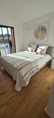 a bedroom with a large white bed with a wooden floor at Casa di Leccia, Superbe Villa à proximité immédiate des plages, piscine privée in Lecci