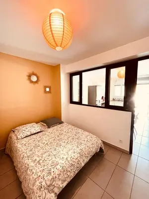 a bedroom with a bed and a large window at Superbe T2 avec place de parking in Ajaccio