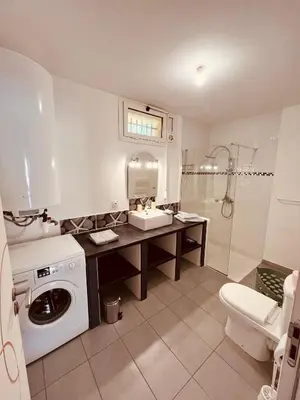 a bathroom with a sink and a washing machine at Superbe T2 avec place de parking in Ajaccio