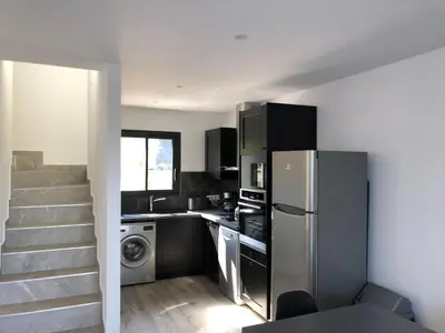 a kitchen with a stainless steel refrigerator and a staircase at Corsica Townhouse near Canella Beach in Favone