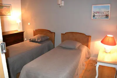 a bedroom with two beds and a table with a lamp at a Casa in Calenzana