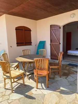 a patio with a table and chairs and a bed at GRANDE VILLA TIZZANO A 200 M DE LA PLAGE 18 PERS in Sartène
