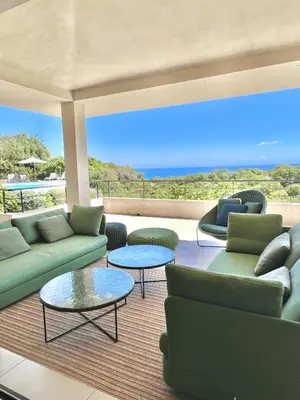 a living room with couches and tables and the ocean at Villa A Muredda in Sainte-Lucie de Porto-Vecchio