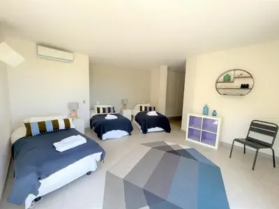 a bedroom with two beds and a chair at Villa A Muredda in Sainte-Lucie de Porto-Vecchio