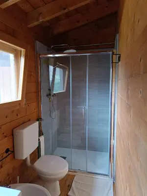 a bathroom with a toilet and a glass shower at Chalet Maria in Bonifacio