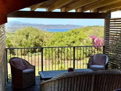 a porch with two chairs and a table on a balcony at Chalet Maria in Bonifacio