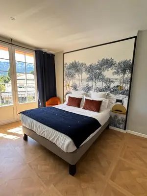 a bedroom with a bed with a large painting on the wall at Grand Hôtel de la Scala in Calacuccia