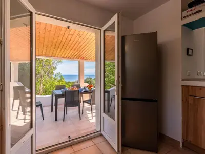 a kitchen with a sliding glass door leading to a dining table at Holiday Home Villa Bruzzi by Interhome in Pianottoli-Caldarello