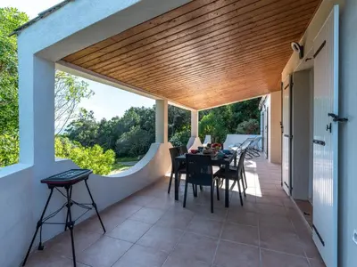 a patio with a wooden ceiling and a table and chairs at Holiday Home Villa Bruzzi by Interhome in Pianottoli-Caldarello