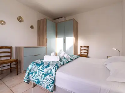 a bedroom with a large white bed and two chairs at Holiday Home Villa Bruzzi by Interhome in Pianottoli-Caldarello