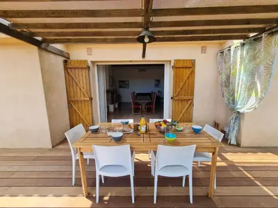 a wooden table and chairs on a patio at Holiday Home La Girelle by Interhome in Porto-Vecchio