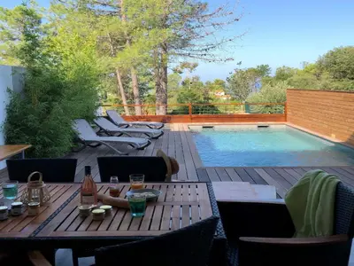 a patio with a table and chairs next to a swimming pool at Les Jardins d'Eve, Solenzara, townhouse with private pool in Favone