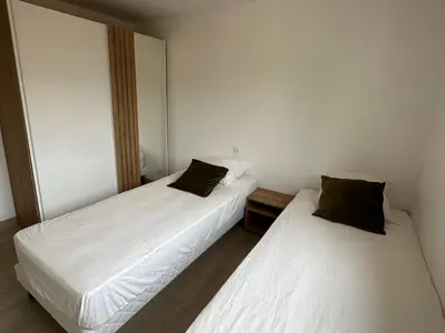 two beds in a room with white sheets and black pillows at Alivu - Appartement Moderne Avec Terrasse in Cargèse