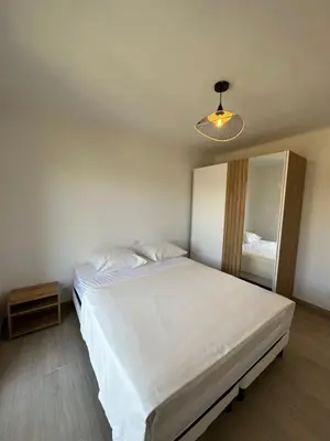 a bedroom with a large white bed and a light at Alivu - Appartement Moderne Avec Terrasse in Cargèse