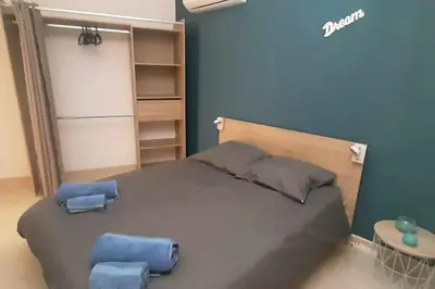 a bedroom with a large bed with two blue stools at appartement en rez de jardin in Foce
