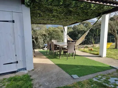 a patio with a table and chairs on grass at appartement en rez de jardin in Foce