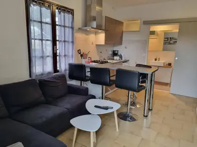 a living room with a couch and a kitchen at appartement en rez de jardin in Foce
