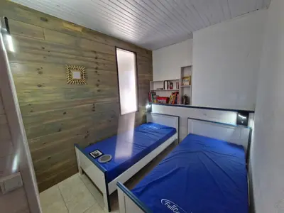 a bedroom with a blue bed and a wooden wall at appartement en rez de jardin in Foce