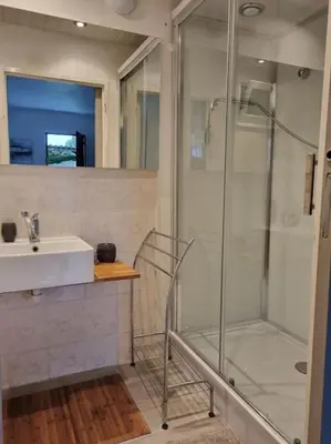 a bathroom with a glass shower and a sink at appartement en rez de jardin in Foce