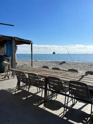 a wooden table and chairs on the beach at Caravane janis on the beach in Lucciana