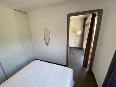 a bedroom with a bed and a clock on the wall at Mini villa Ghjulia Porto-Vecchio proche des plages in Porto-Vecchio