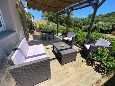 a patio with chairs and a table on a deck at Mini villa Ghjulia Porto-Vecchio proche des plages in Porto-Vecchio