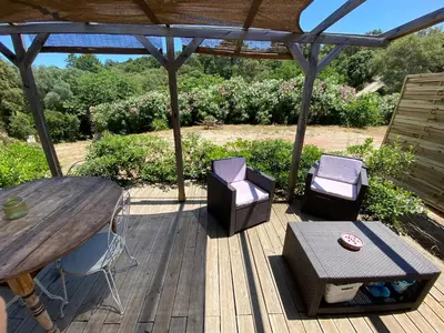 a wooden deck with a table and chairs and a table and a table and chairs at Mini villa Ghjulia Porto-Vecchio proche des plages in Porto-Vecchio