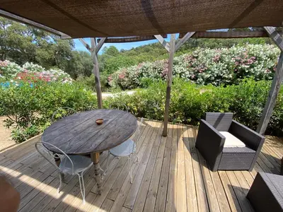 a wooden deck with a table and chairs and flowers at Mini villa Ghjulia Porto-Vecchio proche des plages in Porto-Vecchio