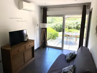 a living room with a tv on a dresser and a sliding glass door at Mini villa Ghjulia Porto-Vecchio proche des plages in Porto-Vecchio