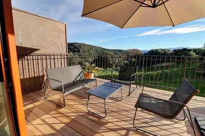 a patio with three chairs and an umbrella at Maison U CASTAGNU in Santa-Reparata-di-Balagna