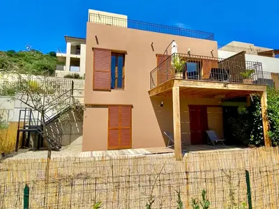 a house with a balcony on top of a fence at Maison U CASTAGNU in Santa-Reparata-di-Balagna