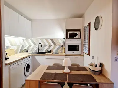 a white kitchen with a table and a stove at Mini Villa 69 - Piscine chauffée in Serra-di-Ferro
