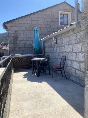 a patio with two chairs and a table with an umbrella at Bel appartement au coeur du village de Sartene in Sartène