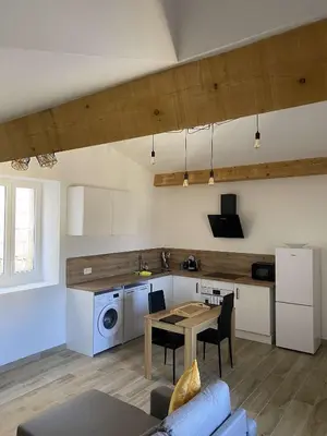 a living room with a table and a kitchen at Bel appartement au coeur du village de Sartene in Sartène