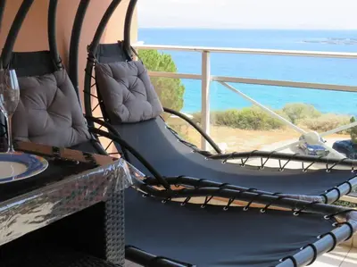 a rocking chair on a balcony with a view of the ocean at Bel app T2 en bord de Mer vue Sanquinaires piscine in Ajaccio