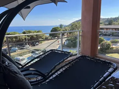 a balcony with a bench and a view of the ocean at Bel app T2 en bord de Mer vue Sanquinaires piscine in Ajaccio