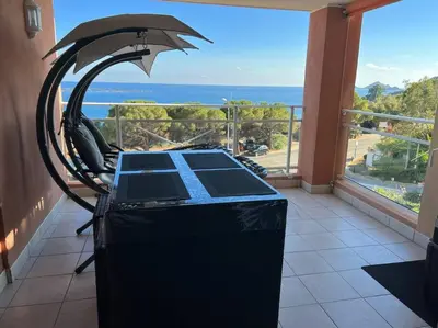 a room with a table with an umbrella and a view of the ocean at Bel app T2 en bord de Mer vue Sanquinaires piscine in Ajaccio