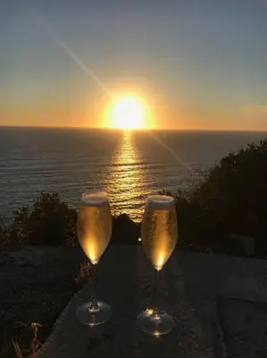 two wine glasses with the sunset in the background at Bel app T2 en bord de Mer vue Sanquinaires piscine in Ajaccio
