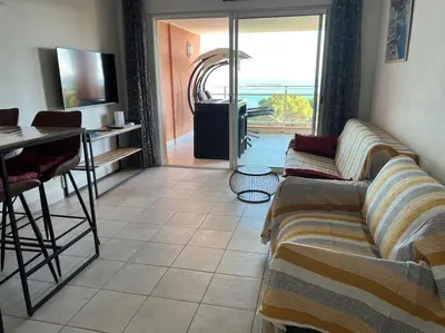 a living room with a couch and a table at Bel app T2 en bord de Mer vue Sanquinaires piscine in Ajaccio