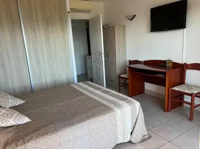 a bedroom with a bed and a desk and a table at Bel app T2 en bord de Mer vue Sanquinaires piscine in Ajaccio