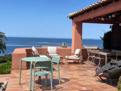 a patio with chairs and tables and a view of the ocean at Maison de Lou in Porticcio