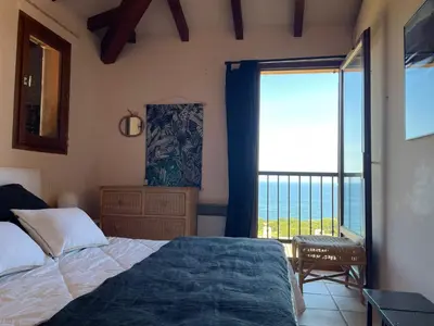 a bedroom with a bed and a large window at Maison de Lou in Porticcio