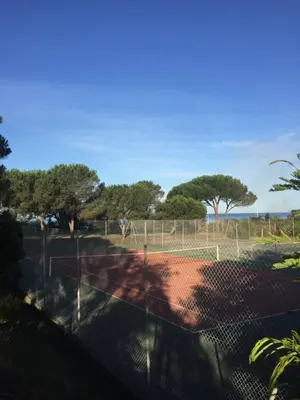 a tennis court behind a chain link fence at Maison de Lou in Porticcio