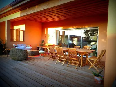 a patio with a table and chairs on a deck at NEW Villa with JACUZZI, near St Cyprien beach in Lecci