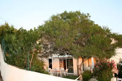 a house with trees and a table and chairs at Maison golfe d'Ajaccio: vue mer in Pietrosella