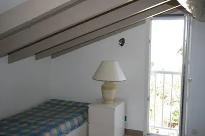 a bedroom with a bed and a lamp on a dresser at Maison golfe d'Ajaccio: vue mer in Pietrosella